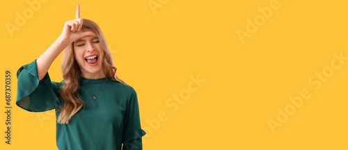 Young woman showing loser gesture on yellow background with space for text photo
