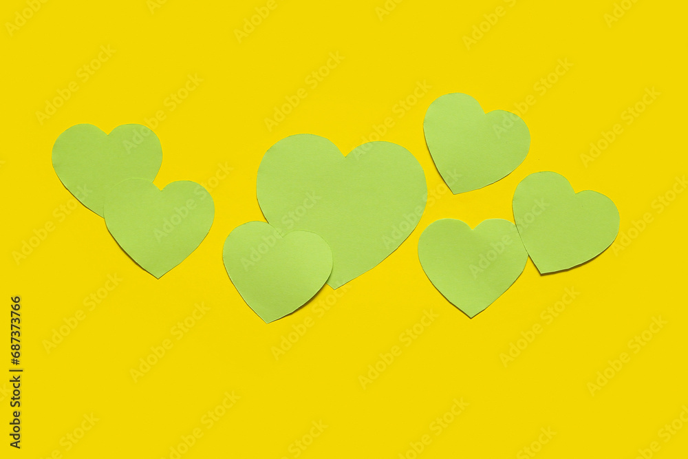 Green paper hearts on yellow background. Valentines Day celebration