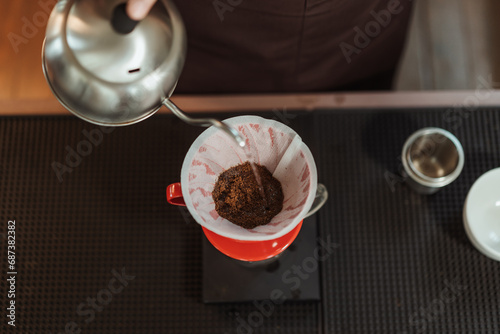 Top view barista holding kettle pour hot water over the coffee powder. Making filter coffee. Drip coffee. photo