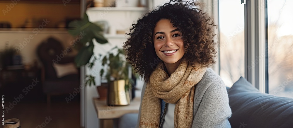 Young woman at home, smiling and posing for a portrait, with curly hair and winter attire, in the living room. Young woman at home, smiling and posing for a portrait, with curly hair and winter attire, in the living room.