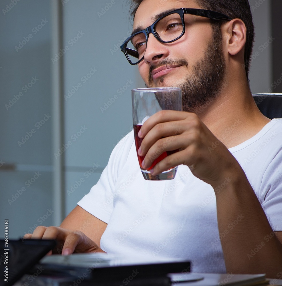 Young man staying late in office to do overtime work Young man staying late in office to do overtime work