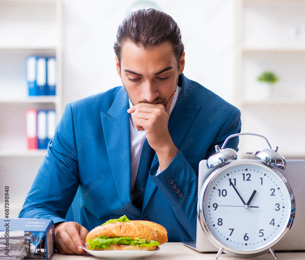 Young male employee having breakfast at workplace Young male employee having breakfast at workplace