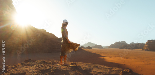 Close up woman tourist in dress stand on cliff barefoot at viewpoint enjoy sunrise on holiday vacation in beautiful Wadi rum desert, Jordan. Popular travel destination middle east