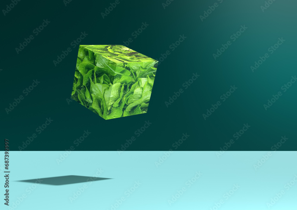 A cube of lettuce leaves levitating against green background.