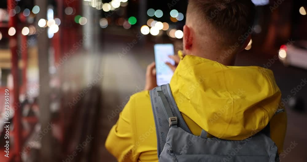 Male courier looking for address in mobile phone for food delivery back view 4k movie slow motion. Mobile app with navigation concept
