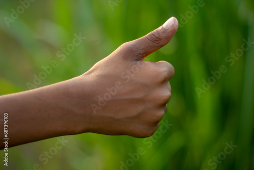 A man has his thumb pointing up and blurred background © Rokonuzzamnan