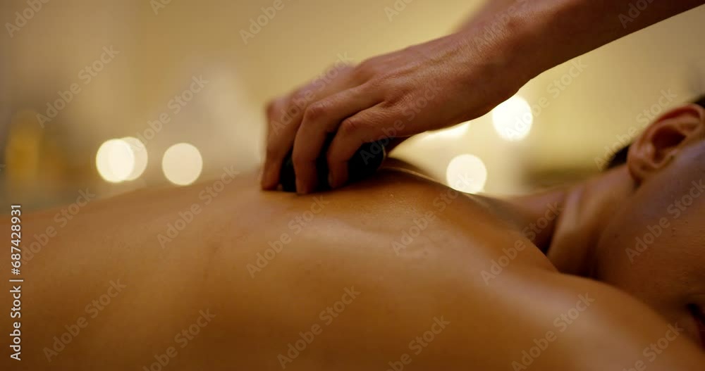 Woman, spa rocks and hot stone massage with skincare and beauty treatment for back pain. Relax, zen and wellness of female person with calm and detox for muscle on a salon bed for skin and body care