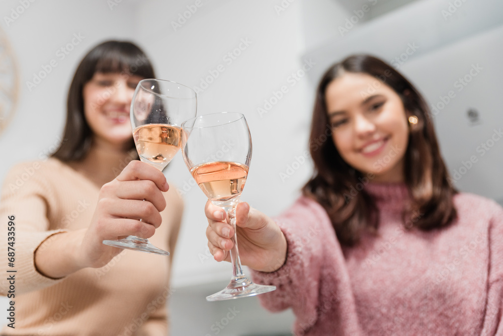 Cheerful women clinking glasses of rose champagne at home Cheerful women clinking glasses of rose champagne at home