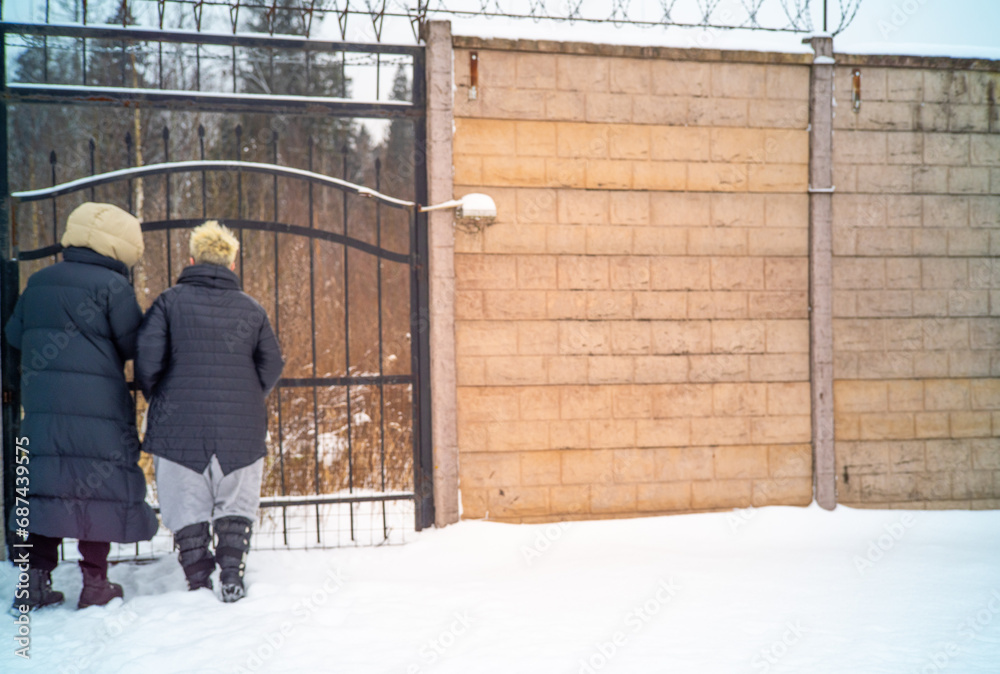 two females standing in front of the closed metal gates, winter scene two females standing in front of the closed metal gates, winter scene
