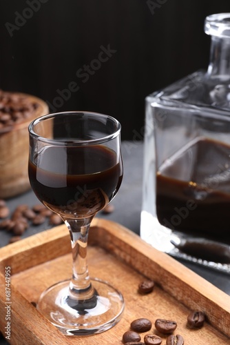 Coffee liqueur and beans on grey table, closeup