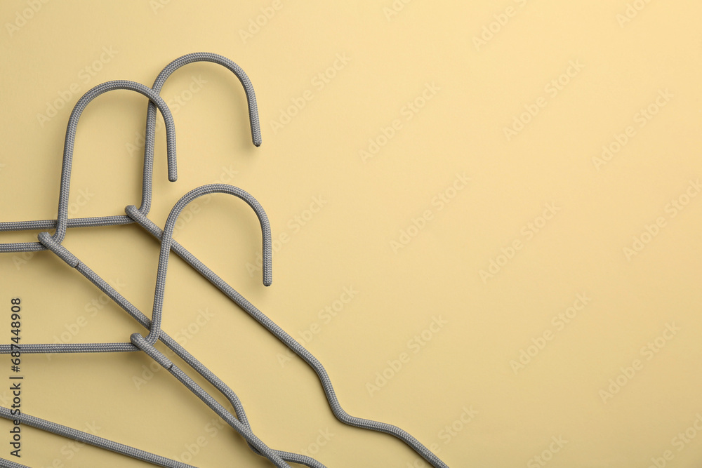 Hangers on pale yellow background, top view. Space for text Hangers on pale yellow background, top view. Space for text