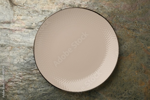 Beautiful beige ceramic plate on gray textured table, top view