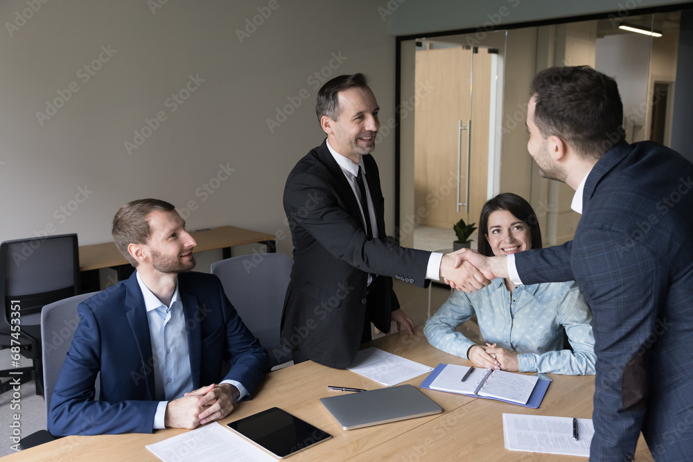 Formal meeting, conclude partnership. Group of businesspeople gathered in board room, make commercial deal, buy and selling company services, shake hands accomplish negotiations, business relations Formal meeting, conclude partnership. Group of businesspeople gathered in board room, make commercial deal, buy and selling company services, shake hands accomplish negotiations, business relations