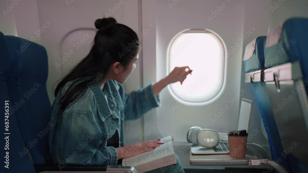 Asian female traveler enjoys her favorite book while flying to a weekend getaway. Immerse in her leisurely journey, combining the joy of reading and the excitement of a long holiday escape. Asian female traveler enjoys her favorite book while flying to a weekend getaway. Immerse in her leisurely journey, combining the joy of reading and the excitement of a long holiday escape.
