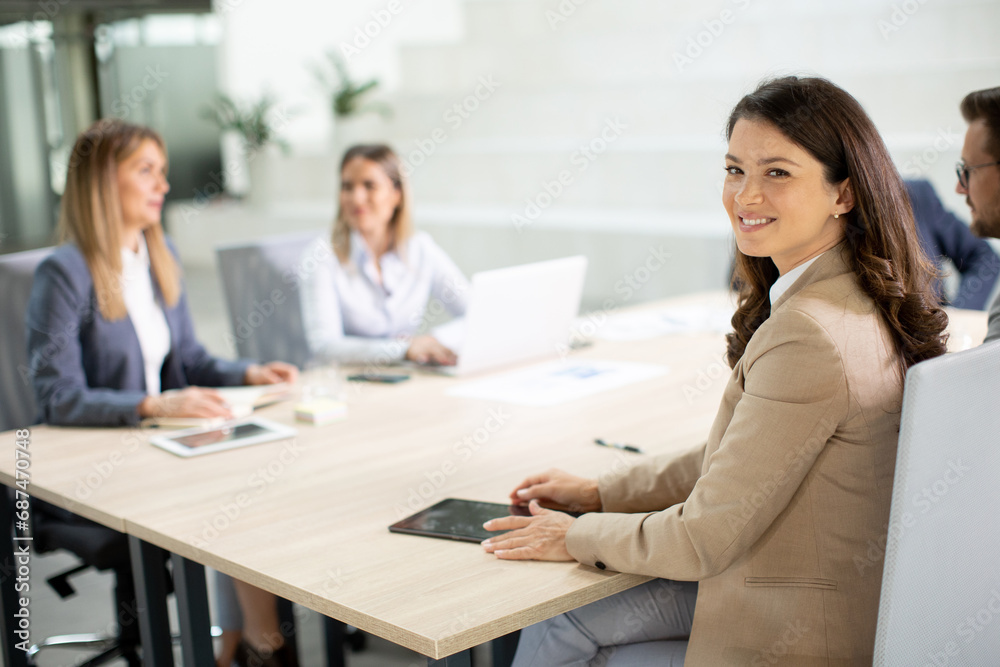 Young woman with digital tablet in the modern office in front of her team