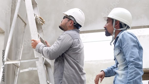 Two engineering worker male climbing ladder, discussing, solving problem construction inspection site compare to blueprint paperwork, Inidian meddle-aged foreman standing together architect employee photo