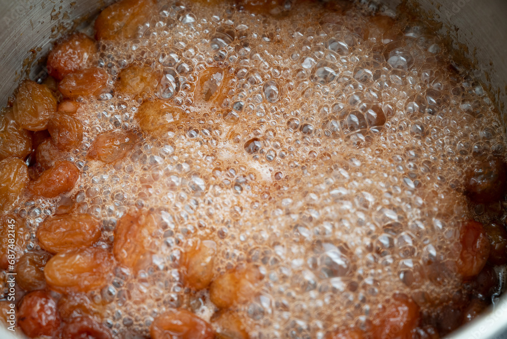 Grapes boiling in a pot with sugar, as part of the process of making homemade jam