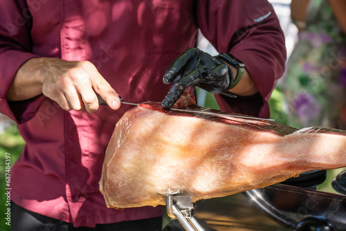 Manos de maestro jamonero cortando jamón al aire lebre