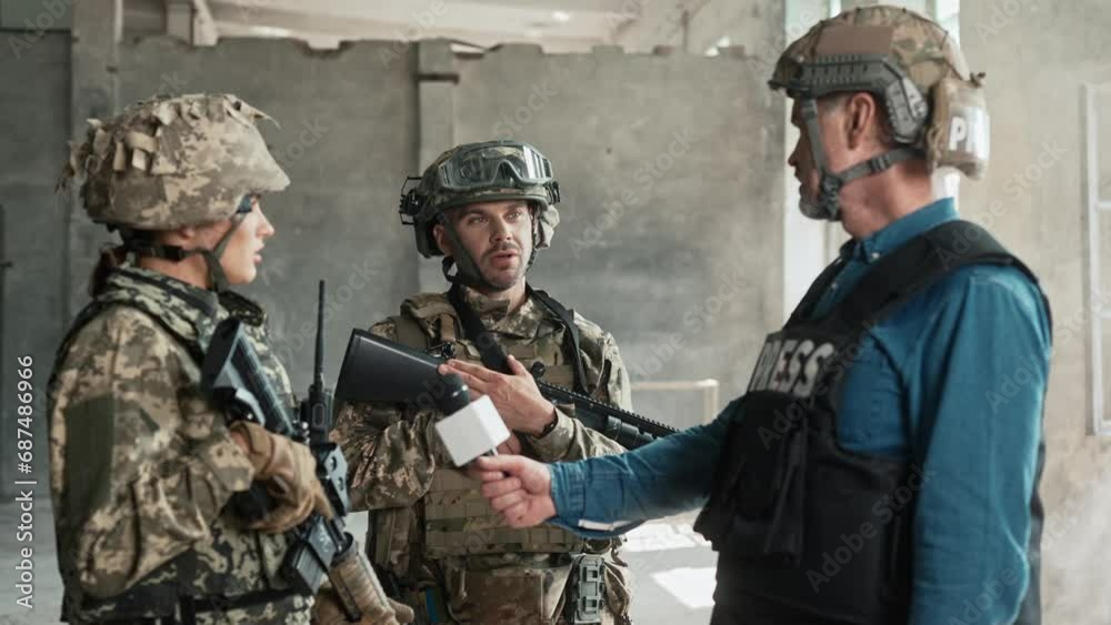Professional reporter with microphone communicating with armed military in smoky building. Soldiers in camouflage telling news from war zone to camera. Interview with military personnel. Professional reporter with microphone communicating with armed military in smoky building. Soldiers in camouflage telling news from war zone to camera. Interview with military personnel.
