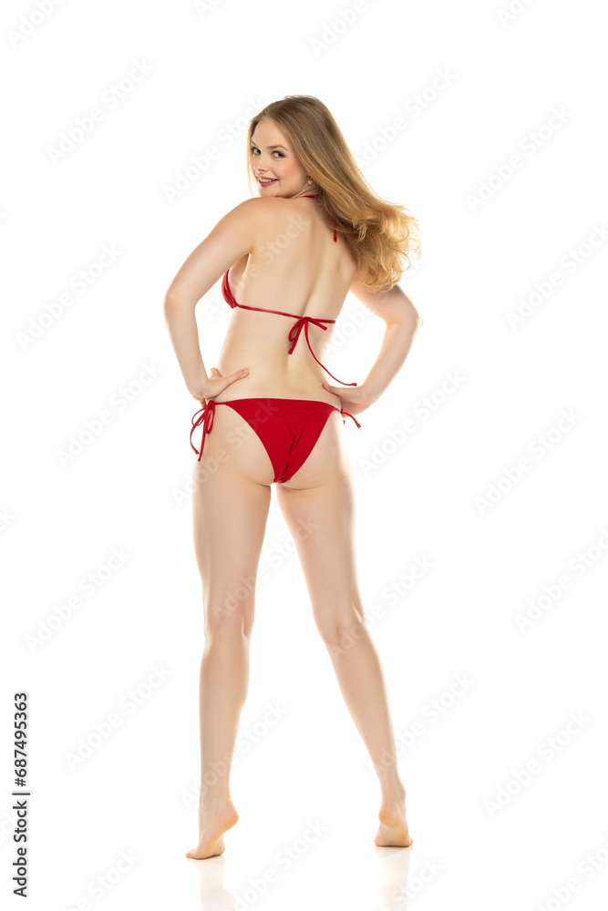 Full body, back view young blond smiling woman in bikini posing on white background Full body, back view young blond smiling woman in bikini posing on white background