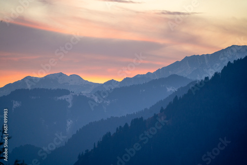 red orange dusk dawn colors over snow covered himalaya mountains and fluffy clouds showing hill stations in jhibbi kullu manali © Memories Over Mocha