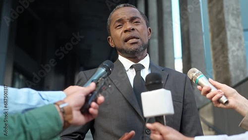 African American politician or entrepreneur giving speech at press conference. Intelligent man with black elegant costume responding on journalists questions. Public performance. TV media.