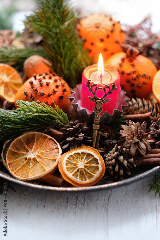 Candle, deer amulet, cinnamon, cones, decorated oranges and dry orange slices on table. Christmas holiday. Winter ritual for Yule sabbat. Festive winter season. close up. selective focus Candle, deer amulet, cinnamon, cones, decorated oranges and dry orange slices on table. Christmas holiday. Winter ritual for Yule sabbat. Festive winter season. close up. selective focus