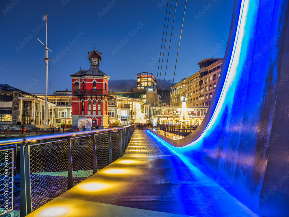 Obraz premium Waterfront suspension bridge and clock tower lit up at night, Cape Town, South Africa