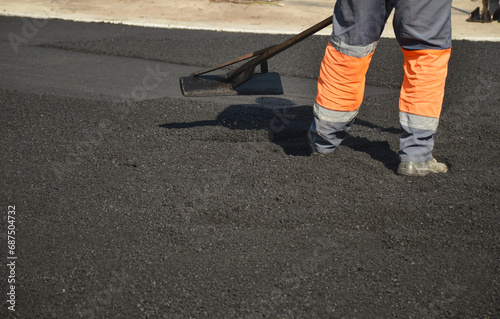 worker with  rake on asphalt