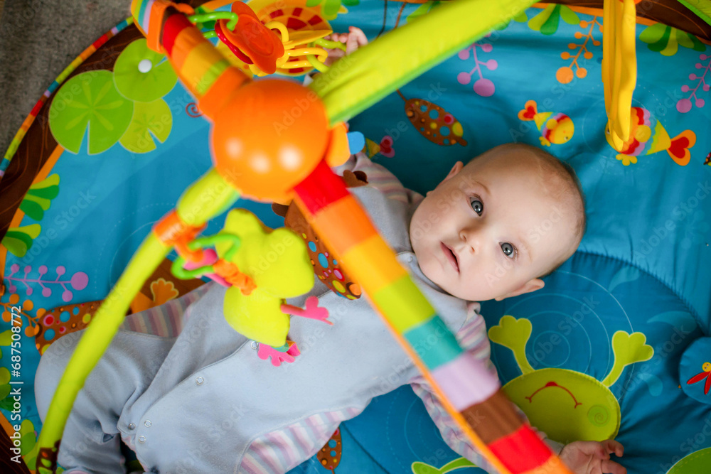 Fototapeta premium a small child lies on a children's educational play mat