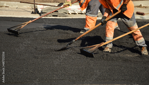workers with rakes level the asphalt mixture photo