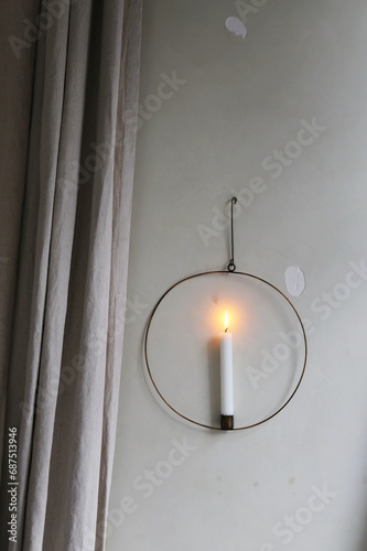 candle in a round candlestick on a white wall
