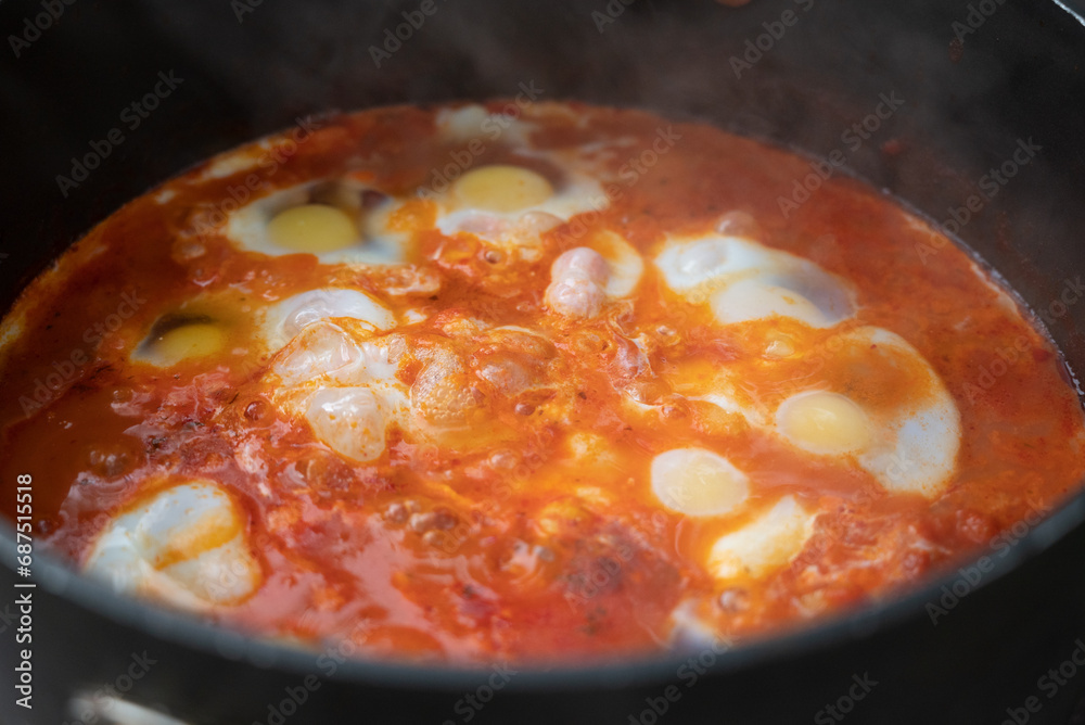 Shakshouka, a traditional dish of poached eggs in a sauce of tomatoes, harissa, olive oil, red peppers, onion and garlic, spiced with cumin, paprika and cayenne pepper Shakshouka, a traditional dish of poached eggs in a sauce of tomatoes, harissa, olive oil, red peppers, onion and garlic, spiced with cumin, paprika and cayenne pepper