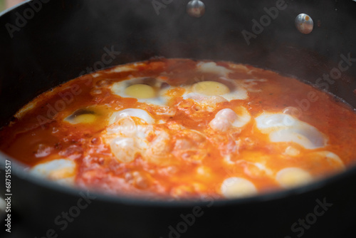 Shakshouka, a traditional dish of poached eggs in a sauce of tomatoes, harissa, olive oil, red peppers, onion and garlic, spiced with cumin, paprika and cayenne pepper