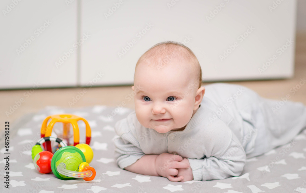 a small cute child lies on the floor on his tummy and looks at colorful educational toys a small cute child lies on the floor on his tummy and looks at colorful educational toys