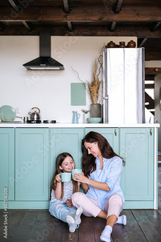Happy mother holding cup of coffee and giving to smell beverage to daughter