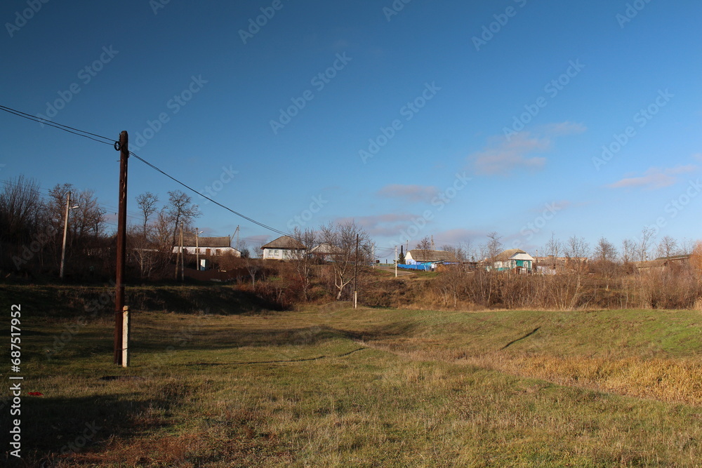A field with power lines and houses in the background