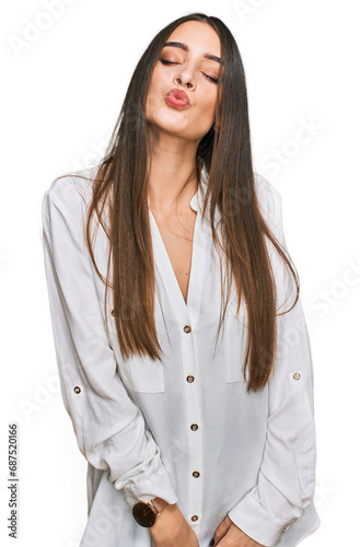 Young beautiful woman wearing casual white shirt looking at the camera blowing a kiss on air being lovely and sexy. love expression. © Krakenimages.com