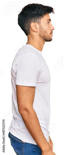 Young handsome man wearing casual white tshirt looking to side, relax profile pose with natural face with confident smile.