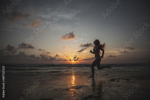 A beautiful girl in a swimsuit jumps at sunset. Sunny colorful sunset. Seashore on the beach.