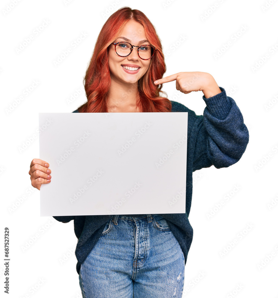 Young redhead woman holding blank empty banner pointing finger to one self smiling happy and proud Young redhead woman holding blank empty banner pointing finger to one self smiling happy and proud