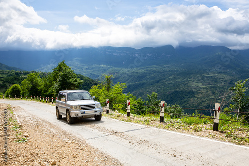 4x4 off-road car driving on a gravel road uphill towards Khvamli Mountain peak in lush green Tskhenistsqali valley in Racha region in Georgia. photo