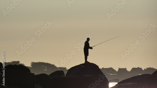 L’homme qui pêche seul sur son rocher photo