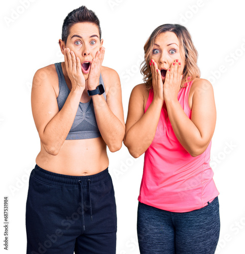 Couple of women wearing sportswear afraid and shocked, surprise and amazed expression with hands on face