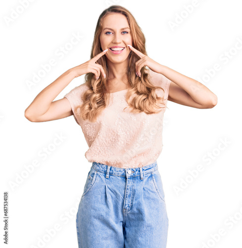 Young beautiful caucasian woman with blond hair wearing casual clothes smiling with open mouth, fingers pointing and forcing cheerful smile