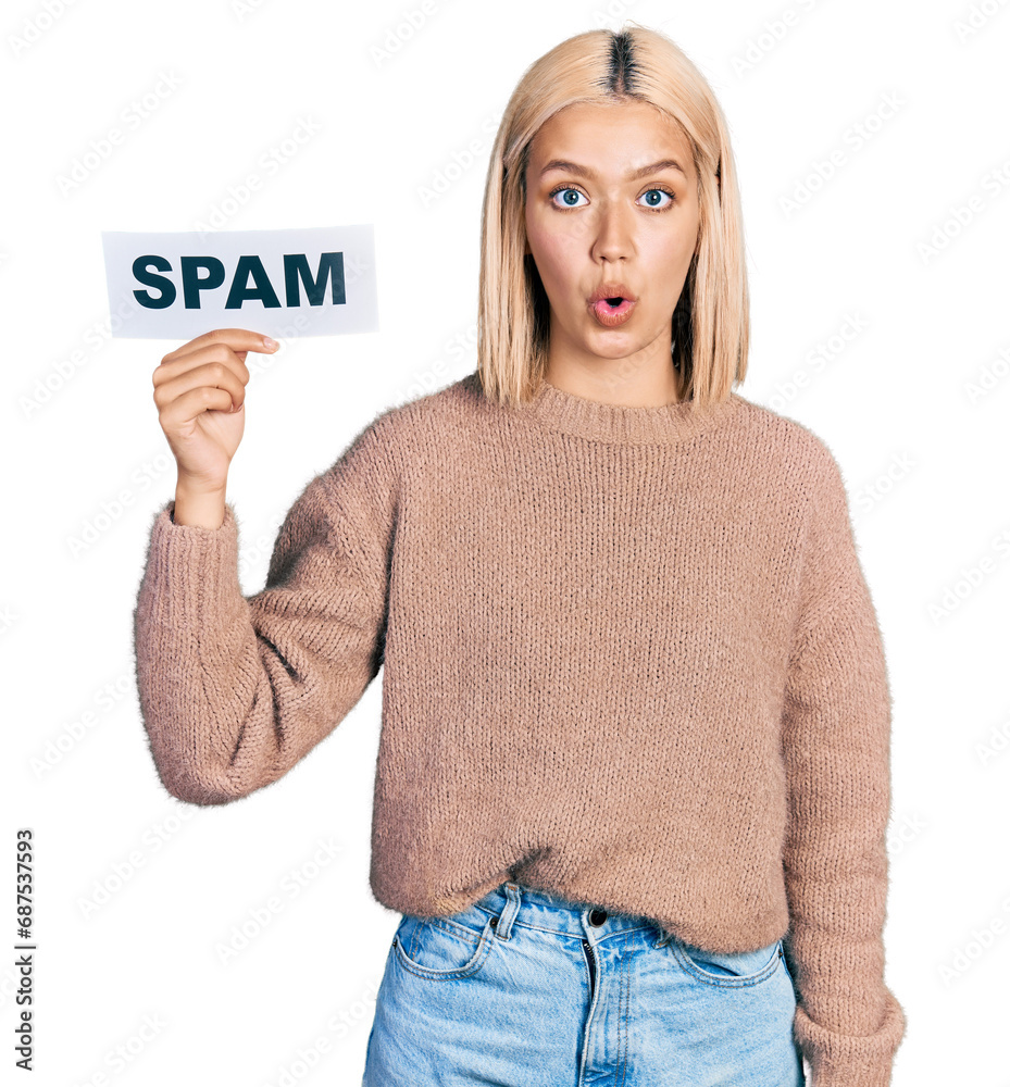 Beautiful young blonde woman holding spam banner scared and amazed with open mouth for surprise, disbelief face Beautiful young blonde woman holding spam banner scared and amazed with open mouth for surprise, disbelief face