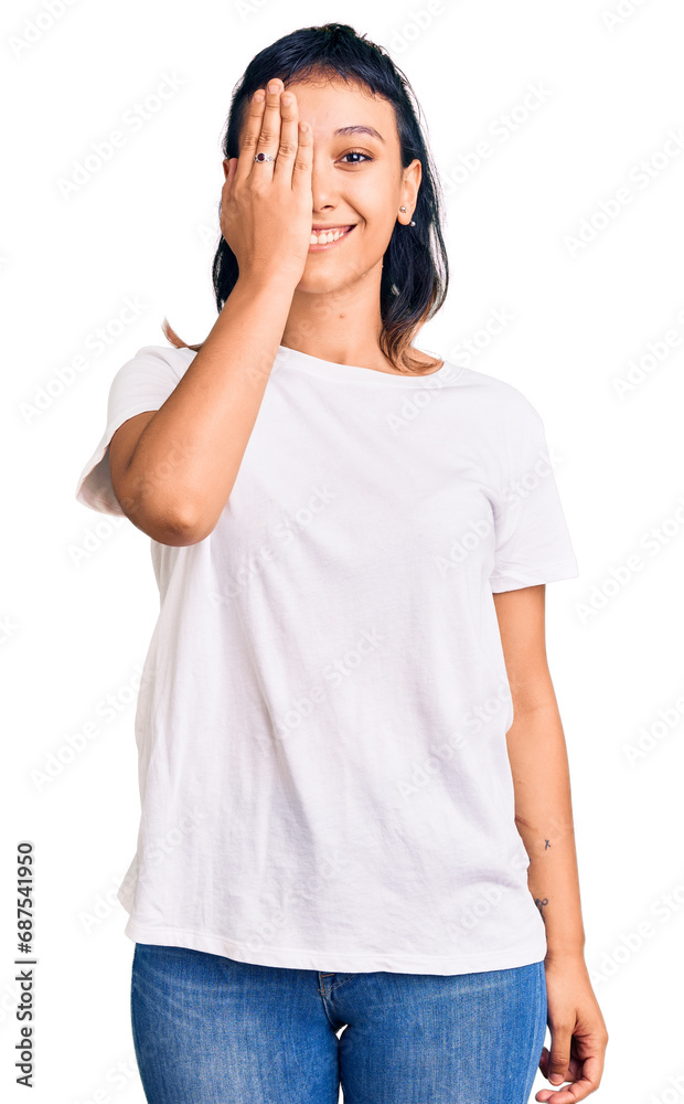 Young woman wearing casual clothes covering one eye with hand, confident smile on face and surprise emotion. Young woman wearing casual clothes covering one eye with hand, confident smile on face and surprise emotion.