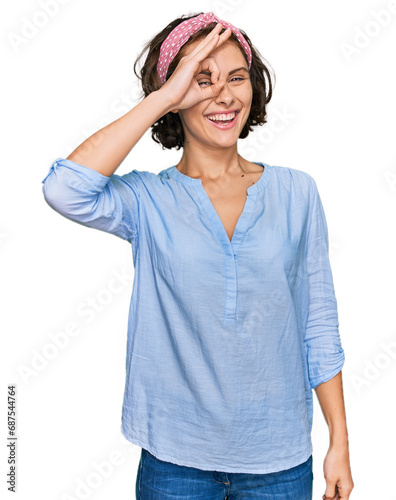 Young hispanic woman wearing casual clothes smiling happy doing ok sign with hand on eye looking through fingers