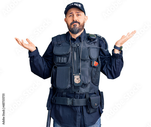 Young handsome man wearing police uniform clueless and confused expression with arms and hands raised. doubt concept.