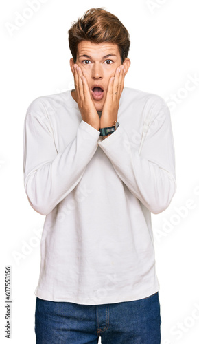 Handsome caucasian man wearing casual white sweater afraid and shocked, surprise and amazed expression with hands on face © Krakenimages.com